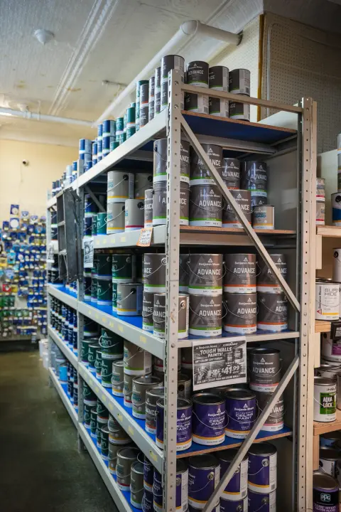 Shelves stacked with cans of Benjamin Moore paint along a store aisle
