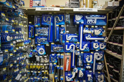 A pegboard wall of drain traps and supply lines in labelled sections