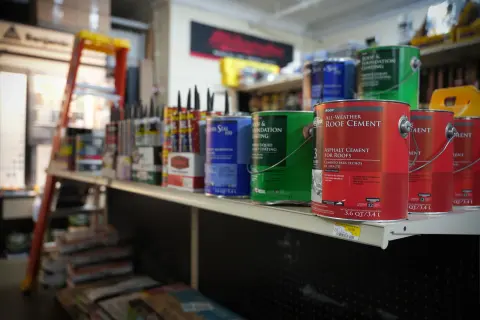 Tubs of all-weather roof cement and roof and foundation coating on a shelf