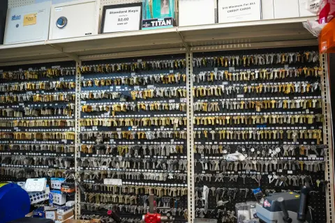 A key-blank wall with a sign advertising standard keys, and safes on the shelf above
