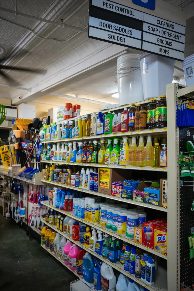 A cleaning supplies aisle beneath signs for soap, detergent, brooms and mops