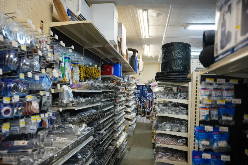 An aisle of shelving stocked with bagged hardware, chain and wire