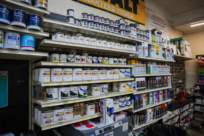 Shelves of primer and paint cans beneath a store banner