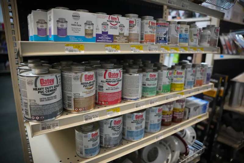 Cans of Oatey PVC cement and primer lined up on a shelf