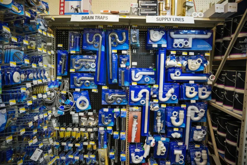 A pegboard wall of drain traps and supply lines in labelled sections