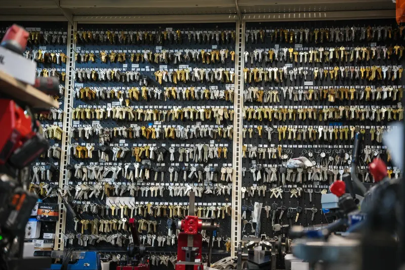 Key-cutting machines in front of a wall of hundreds of key blanks