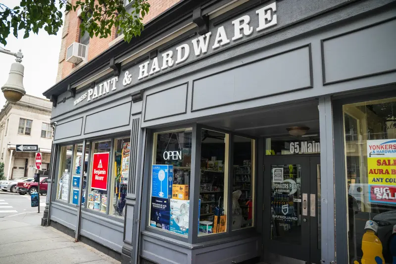 The Yonkers Paint & Hardware storefront at 65 Main Street, its grey facade lettered "Paint & Hardware" with an open sign and Benjamin Moore placard in the window